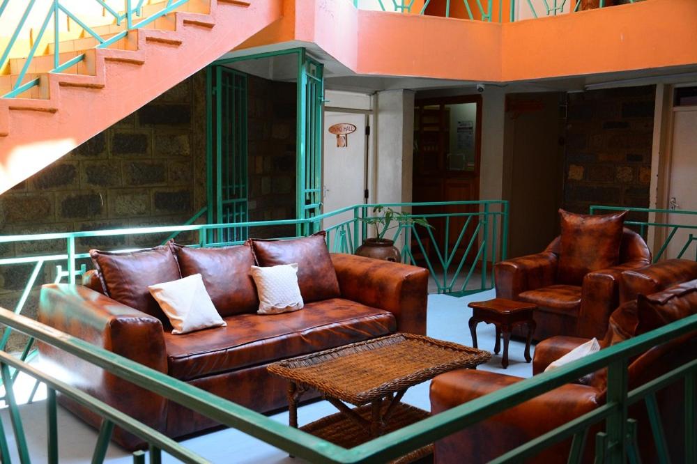 einen Balkon mit Ledersofas, Tischen und Treppen in der Unterkunft New Green Pastures Guest House in Eldoret