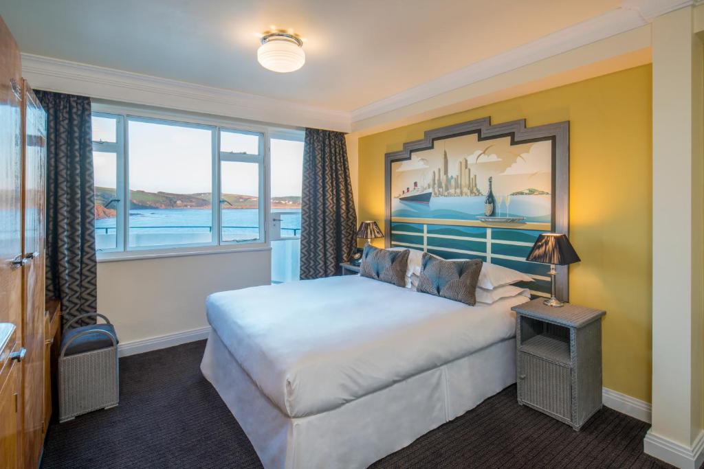 a hotel room with a bed and a large window at Burgh Island Hotel in Bigbury on Sea