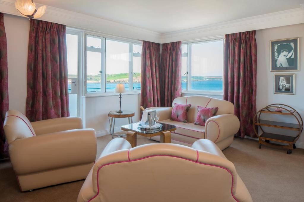 a living room with chairs and a couch and windows at Burgh Island Hotel in Bigbury on Sea