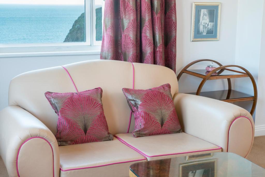 a white couch with two pink pillows on it at Burgh Island Hotel in Bigbury on Sea