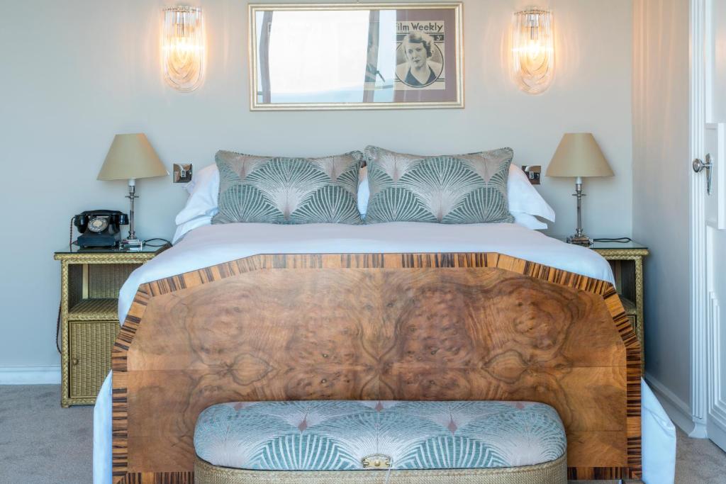 a bedroom with a large bed with a wooden headboard at Burgh Island Hotel in Bigbury on Sea