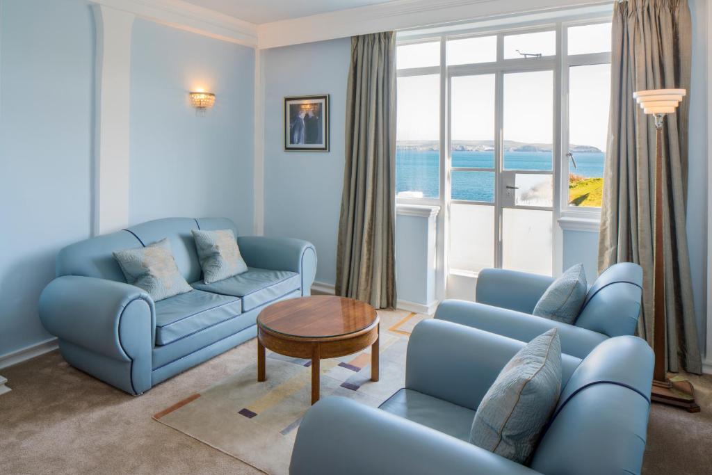 a living room with blue couches and a table at Burgh Island Hotel in Bigbury on Sea