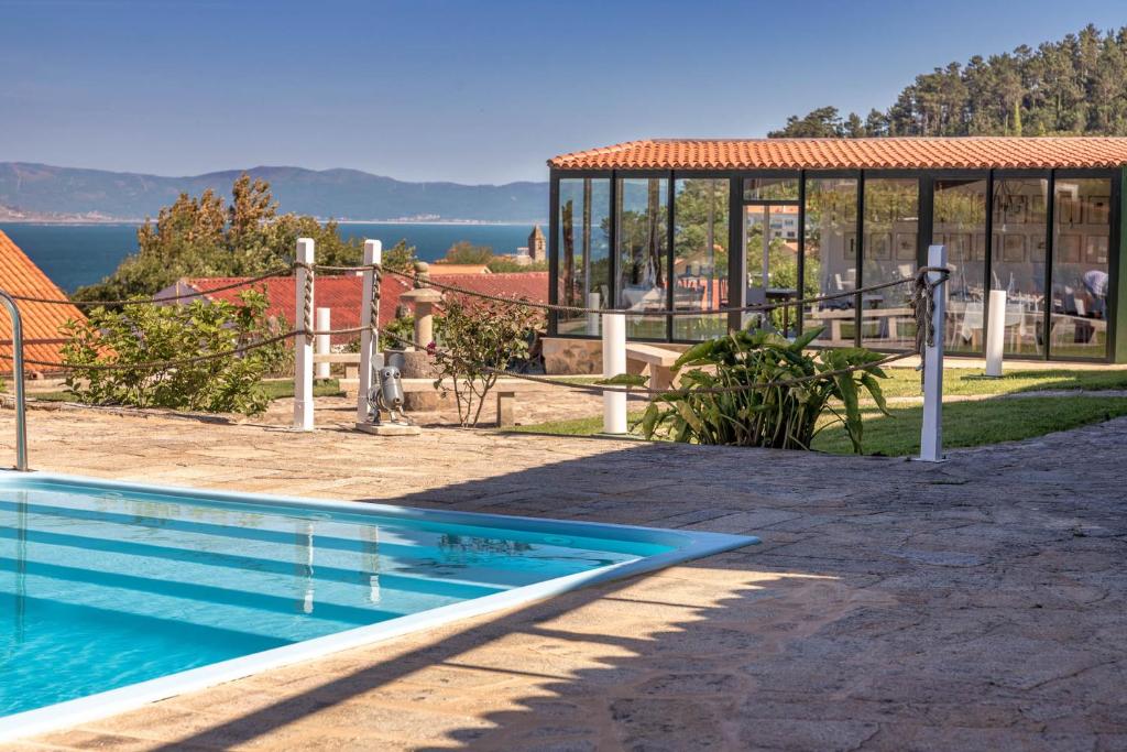 a house with a swimming pool in front of a building at Hotel Rústico Finisterrae in Fisterra