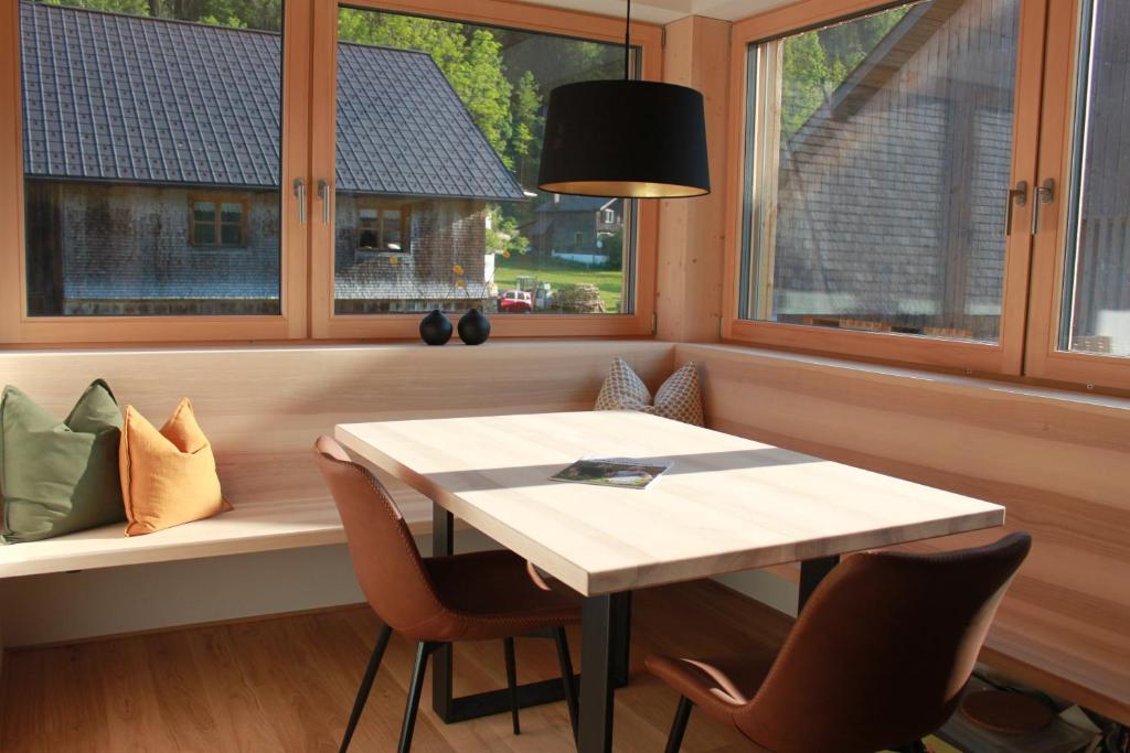 einen Tisch und Stühle in einem Zimmer mit Fenstern in der Unterkunft Kanis 80 in Schnepfau