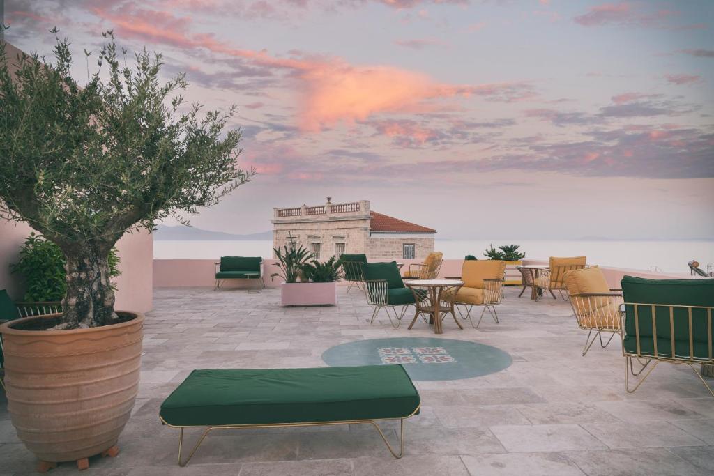 a patio with chairs and tables and a painting of a sky at Aristide Hotel - Small Luxury Hotels of the World in Ermoupoli