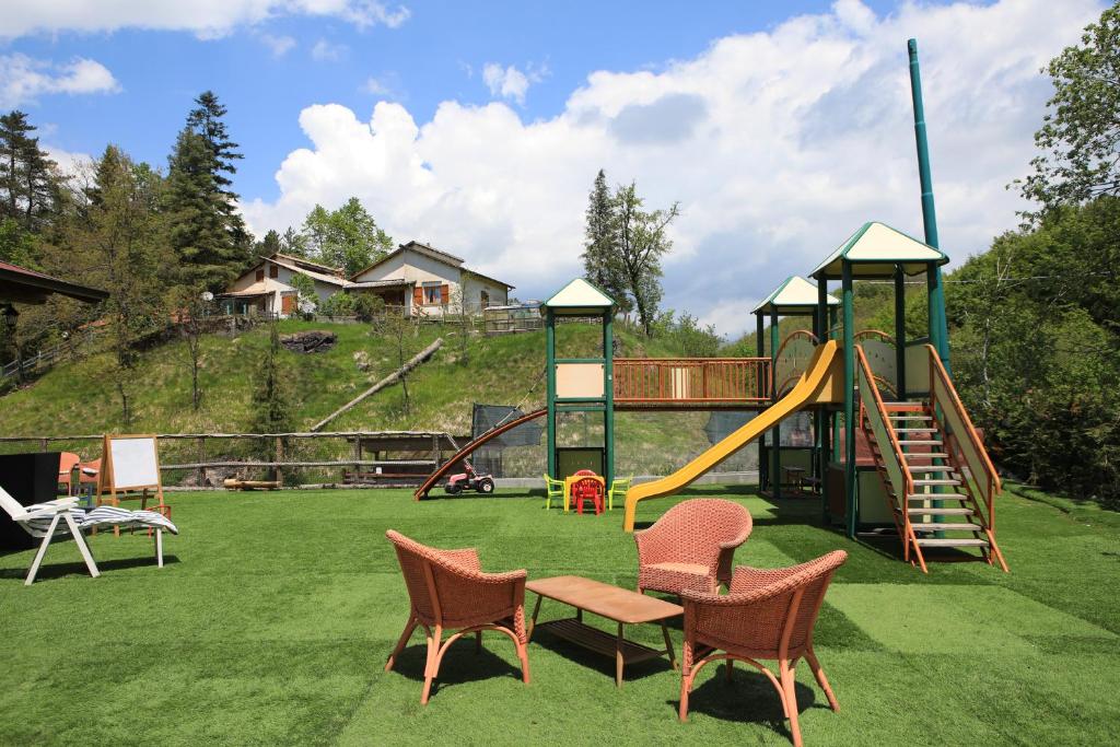 plac zabaw ze zjeżdżalnią i krzesłami na trawie w obiekcie Green Riviera Case Vacanza w mieście Borzonasca