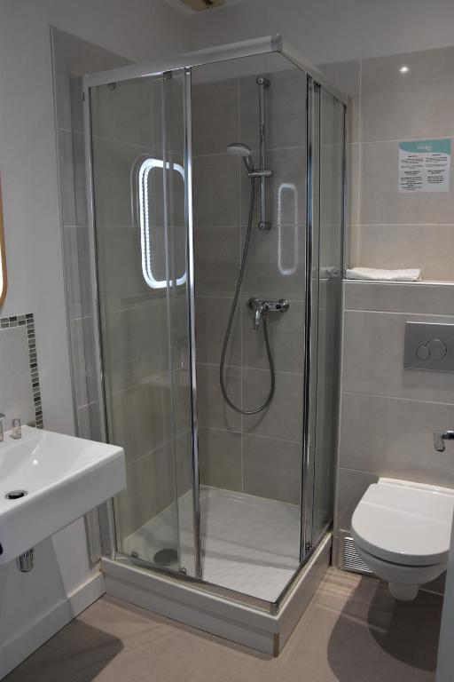 a shower in a bathroom with a sink and a toilet at Hôtel Domaine du Lac Chambon in Murol