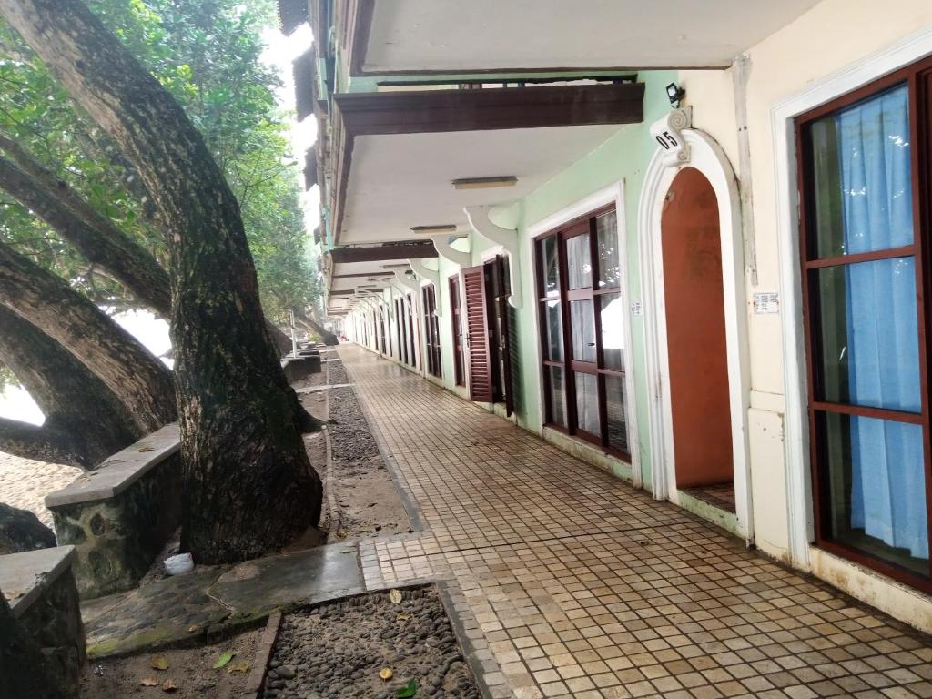 un couloir vide d'un bâtiment avec un arbre dans l'établissement KONDOMINIUM PANTAI CARITA - Neli, à Carita
