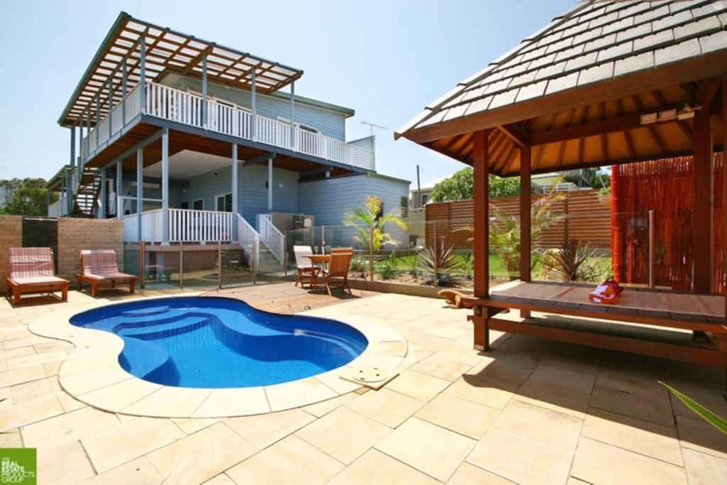 un patio trasero con piscina y una casa en Southview Guest House, en Wollongong