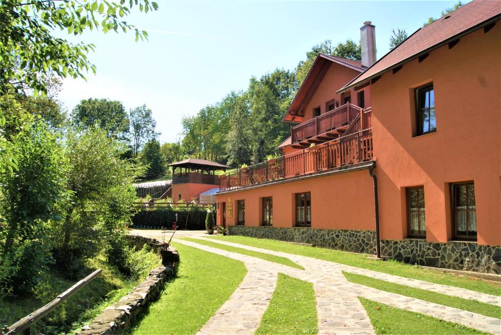 una casa con un patio de césped al lado de un edificio en Penzion Liškův Mlýn en Milešov