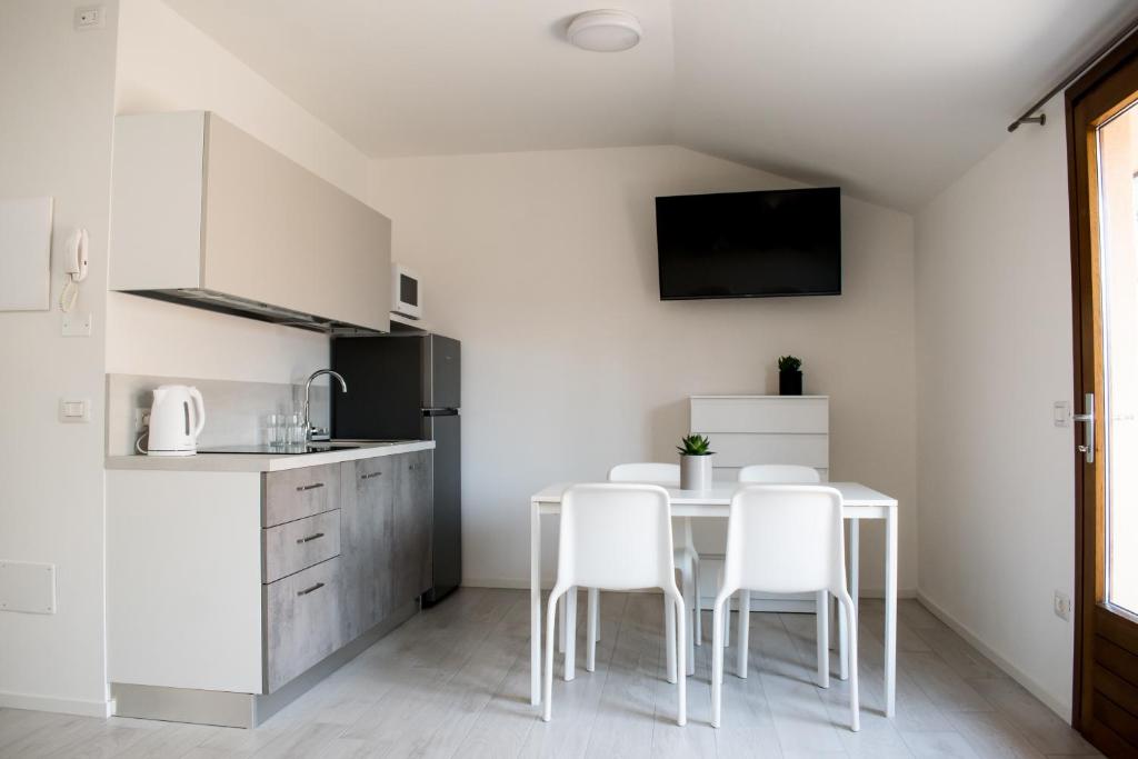 a white kitchen with a table and white chairs at Cà Rita Apartments in Malcesine