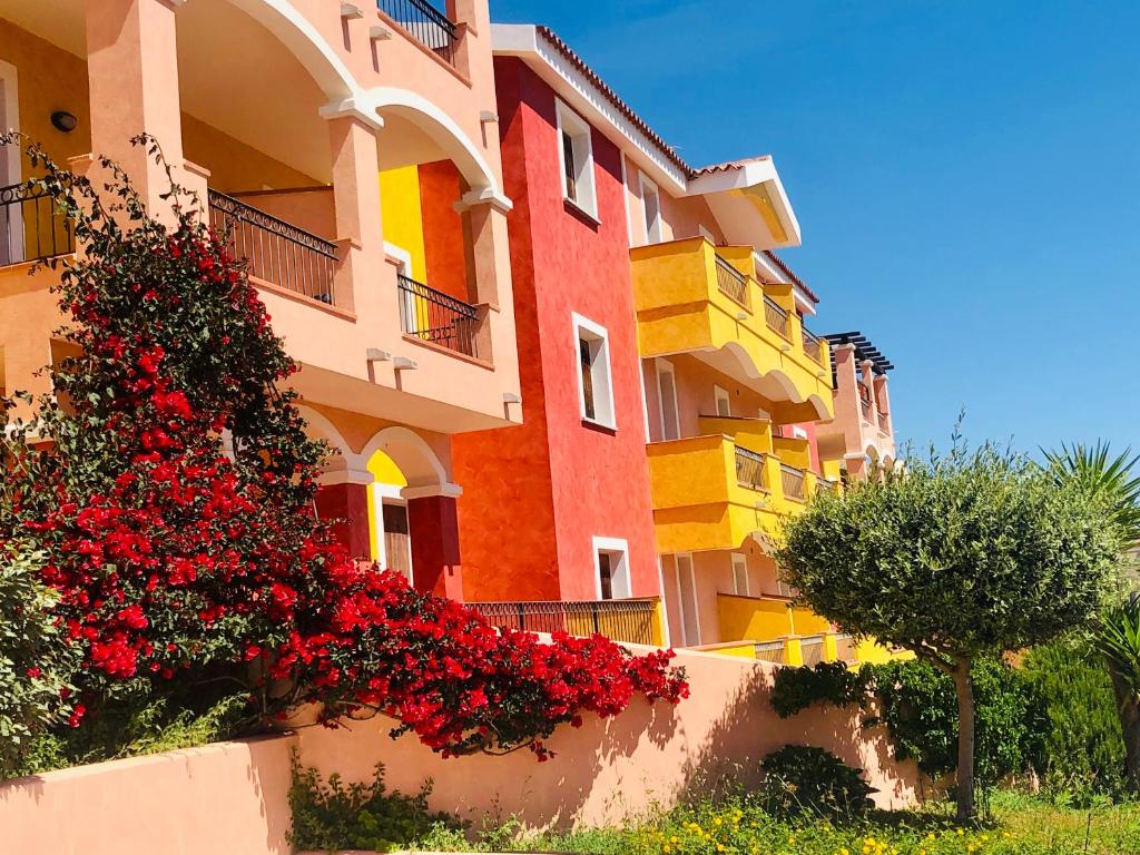 un edificio colorido con flores rojas delante en Le case di Bea en Santa Teresa Gallura