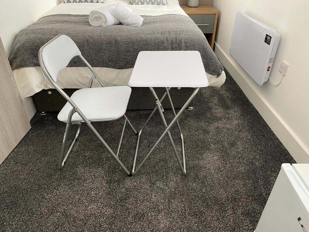 twee witte stoelen en een tafel voor een bed bij 2A SPV Double En-suite Room in Wakefield