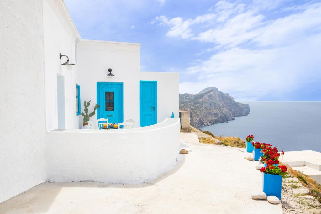 a white building with blue doors and flowers at Nacros Villa Olympos Karpathou in Olympos