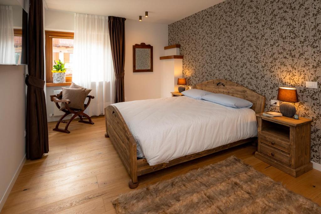 a bedroom with a bed and a desk and a chair at Larici Rooms in Roana