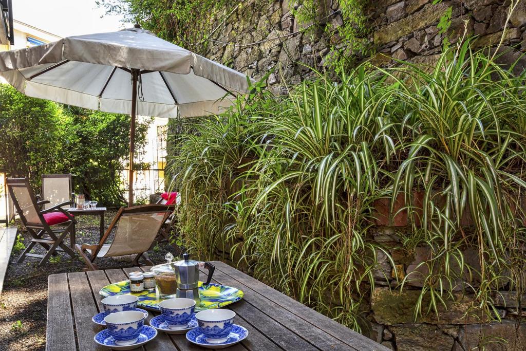 una mesa de madera con platos de comida y una sombrilla en Relax in giardino a due passi dal porto by Wonderful Italy, en Rapallo