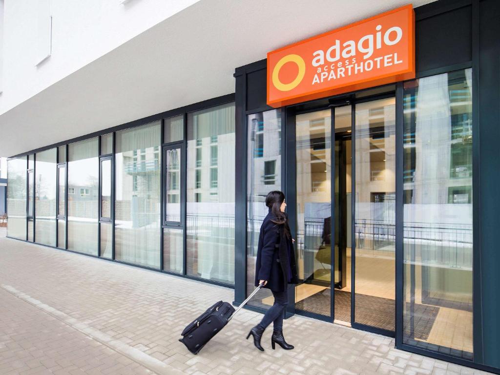 a woman walking in front of a store with a suitcase at Aparthotel Adagio access München City Olympiapark in Munich