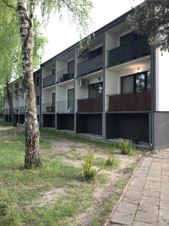 um edifício de apartamentos com varandas e uma árvore em Apart - apartament 12 em Okuninka