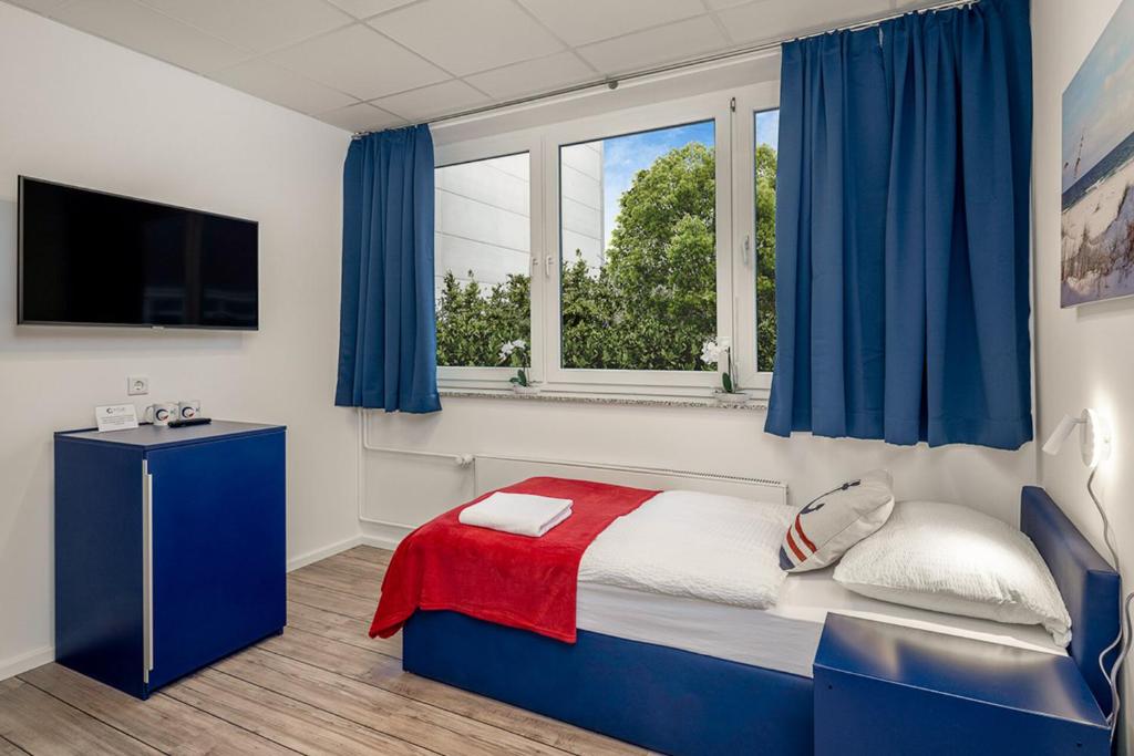 a bedroom with a bed with blue curtains and a tv at Koje Hostel in Hamburg