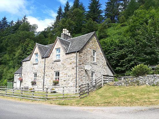 an old stone house on the side of a road at Keeper's Cottage in Lochgilphead