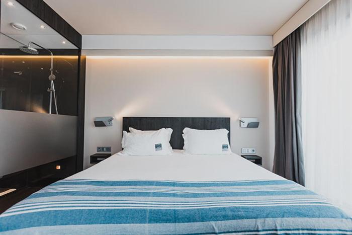 a bedroom with a large white bed with blue stripes at H Boutique Peña Parda in La Herradura