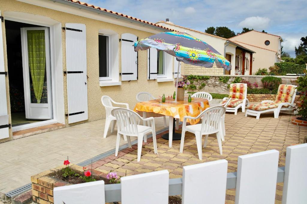 un patio con tavolo, sedie e ombrellone di Vacances à 4 à Brem-sur-Mer a Brem-sur-Mer