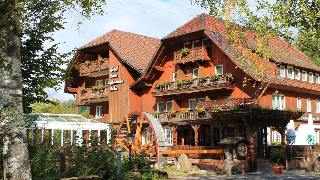 ein großes Holzhaus mit einem Spielplatz davor in der Unterkunft Landhotel Untere Kapfenhardter Mühle in Unterreichenbach