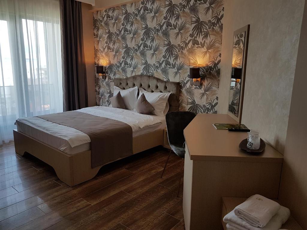 a bedroom with a bed and a desk and a mirror at Hotel Grand Dedal in Mamaia Nord