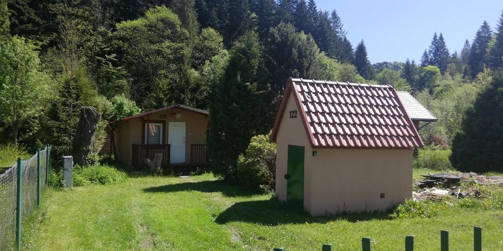 a small house in a field next to a fence at Domek letniskowy przy Orliku Cisna działka in Cisna