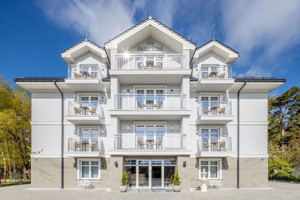a white building with balconies and tables at Villa Baltic Sand in Międzyzdroje