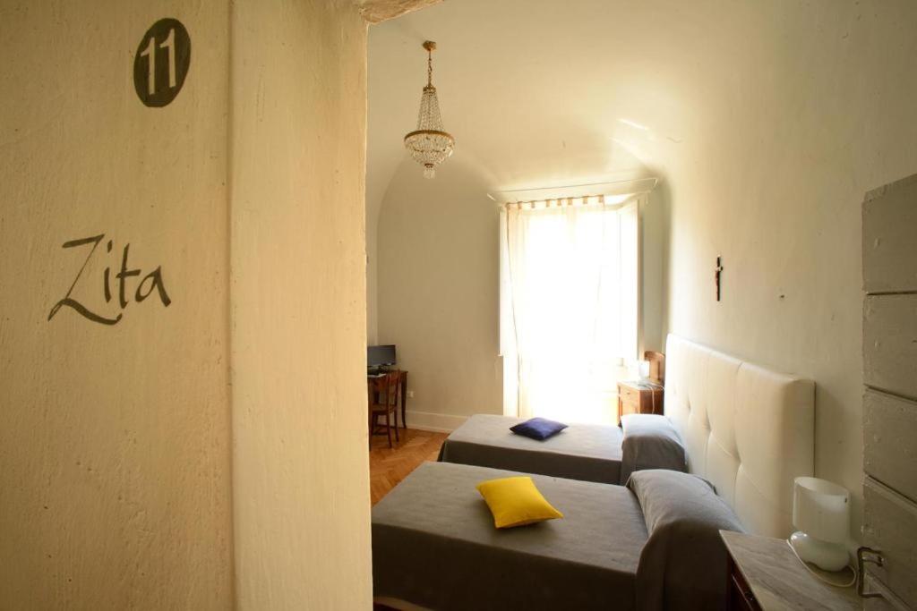 a row of beds in a room with a window at La Foresteria del Convento in Santarcangelo di Romagna