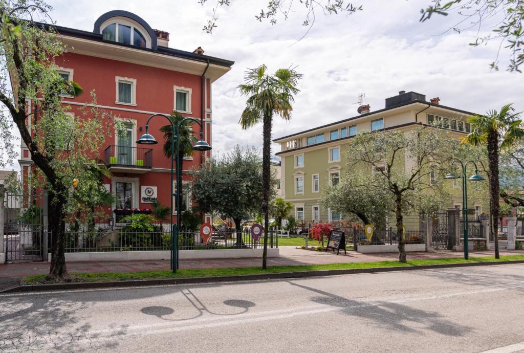 a street in a city with buildings and palm trees at lillil - Popping Holiday in Riva del Garda