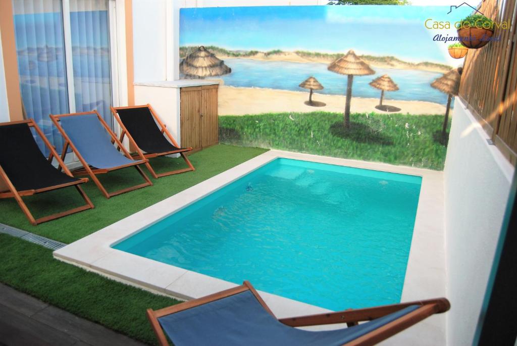 a swimming pool with chairs and a painting on the wall at Casa do Corval in Aldeia do Mato