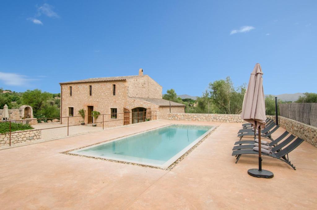 a pool with chairs and an umbrella and a house at YourHouse Sa Riba Villa in Son Carrió