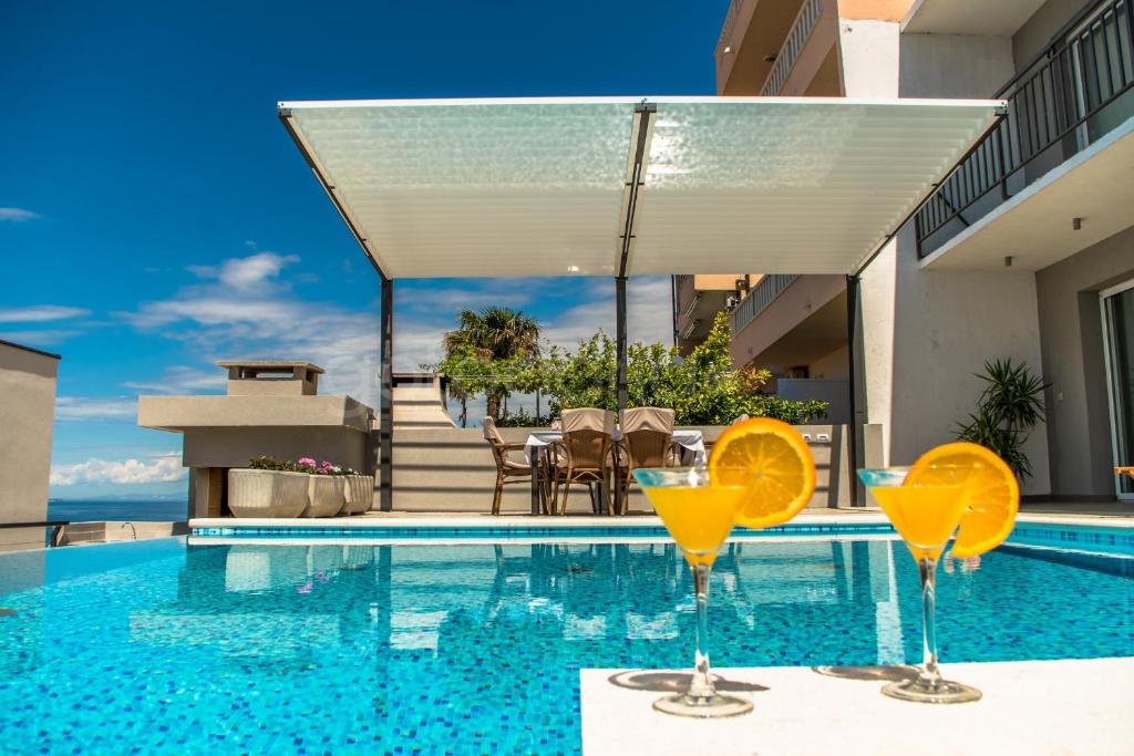 een zwembad met twee martini glazen op een tafel bij Apartment Stanley with Private Pool in Makarska
