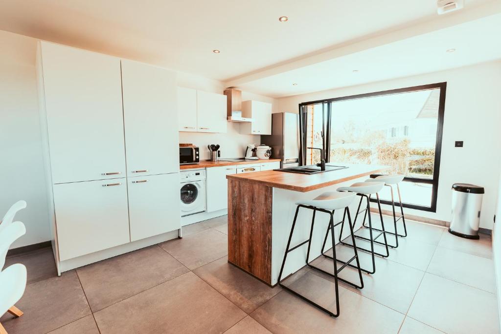 a kitchen with white cabinets and a counter with stools at Le Paradis du petit Rupembert in Wimille