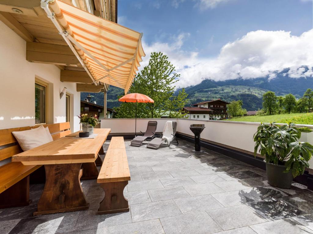 a patio with a wooden table and chairs and an umbrella at Appart Klocker in Kaltenbach