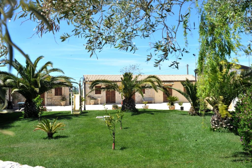 a garden with palm trees and a building at Oasi Di Cava Ispica in Pietre Nere San Zagaria