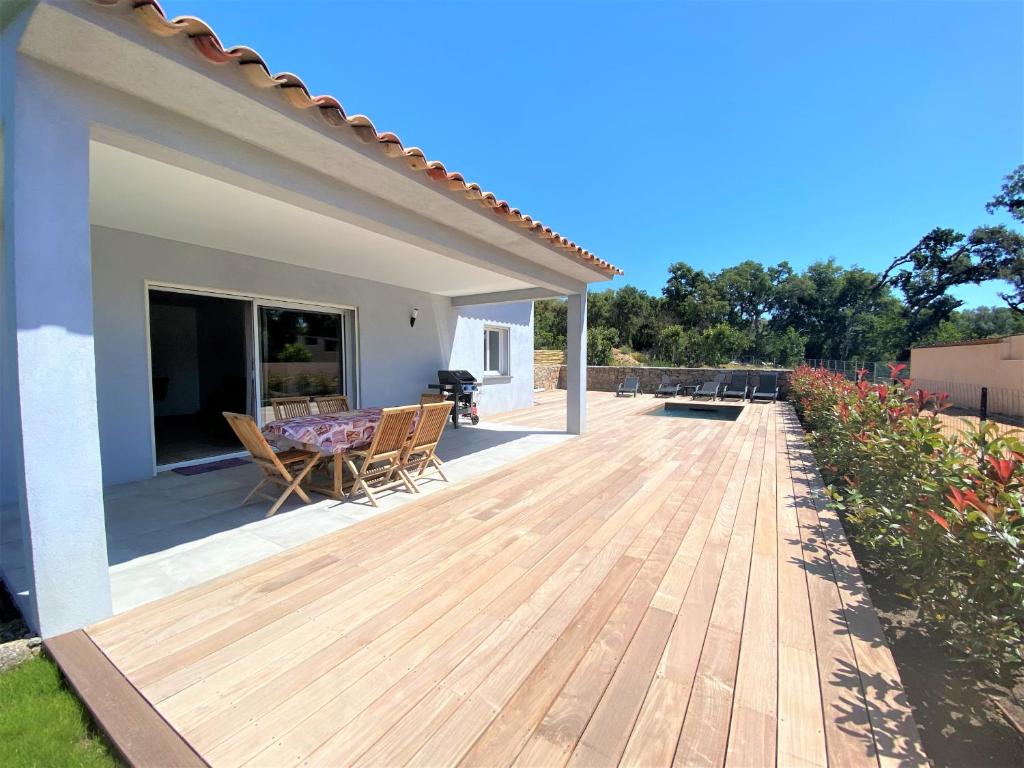 une terrasse en bois avec des chaises et une table sur une maison dans l'établissement Villa deux chambres avec piscine chauffee proche des plages, à Sainte-Lucie de Porto-Vecchio