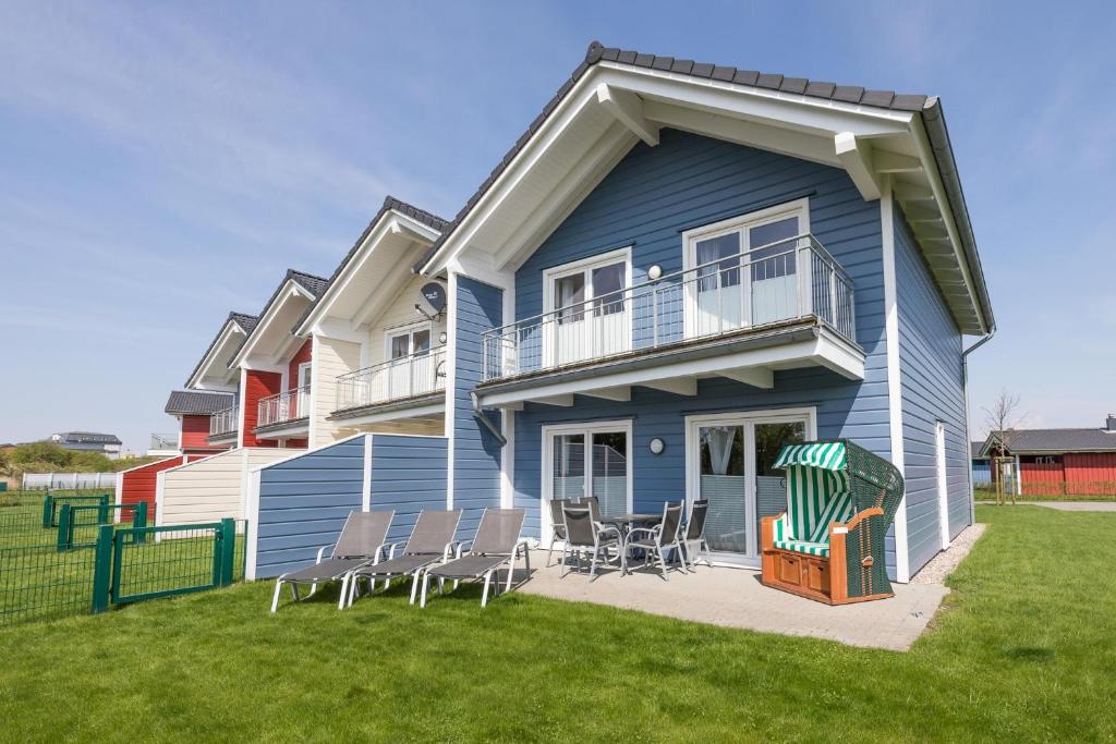 a blue house with chairs on a lawn at Ferienhaus Basstölpel in Dagebüll