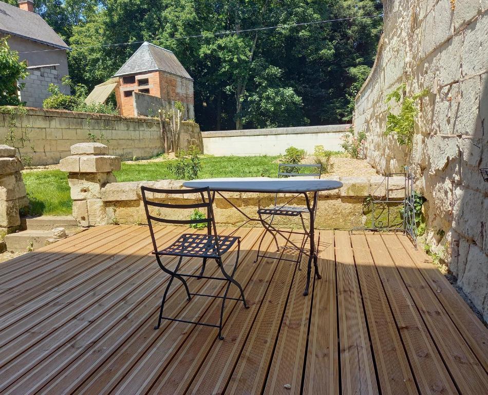 stół i 2 krzesła na drewnianym tarasie w obiekcie L'Eau Reine w mieście Saumur