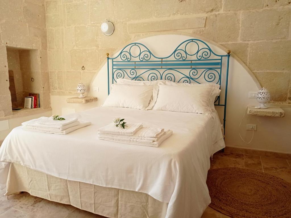 una camera da letto con un letto bianco e asciugamani di Giardino Frannicola a Maglie