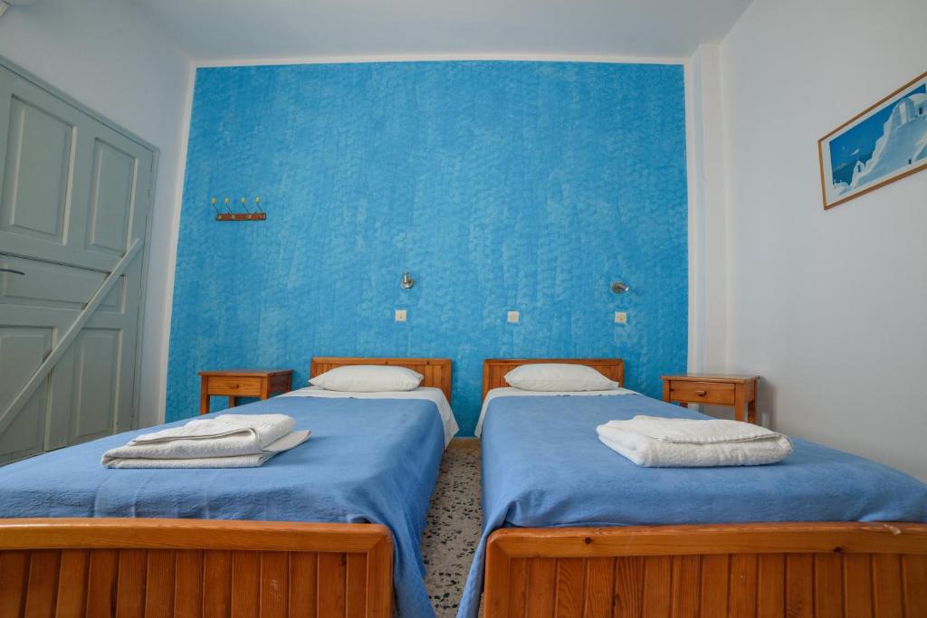 2 letti singoli in una camera con pareti blu di Dilino a Kamari