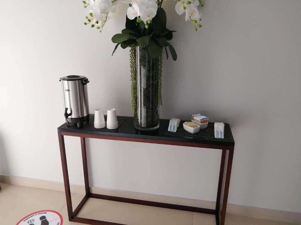 une table noire avec un vase de fleurs sur elle dans l'établissement Vive Place, à Aguascalientes