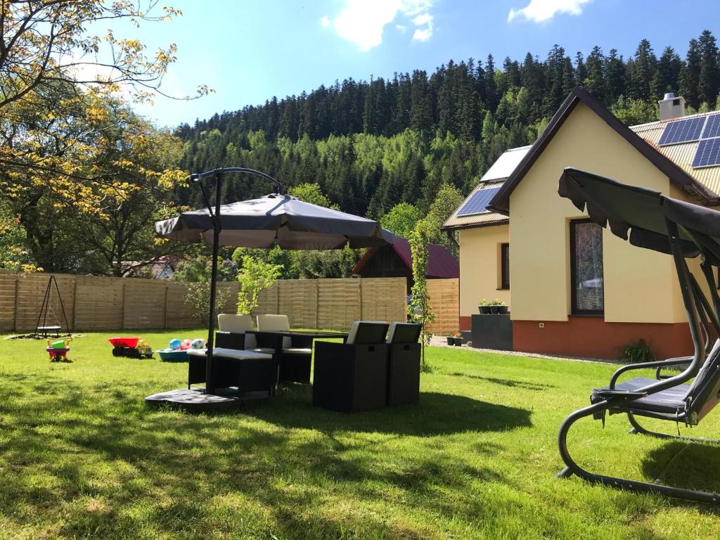 einen Hof mit einem Tisch und einem Sonnenschirm in der Unterkunft Domek Damianki - cały dom in Zawoja