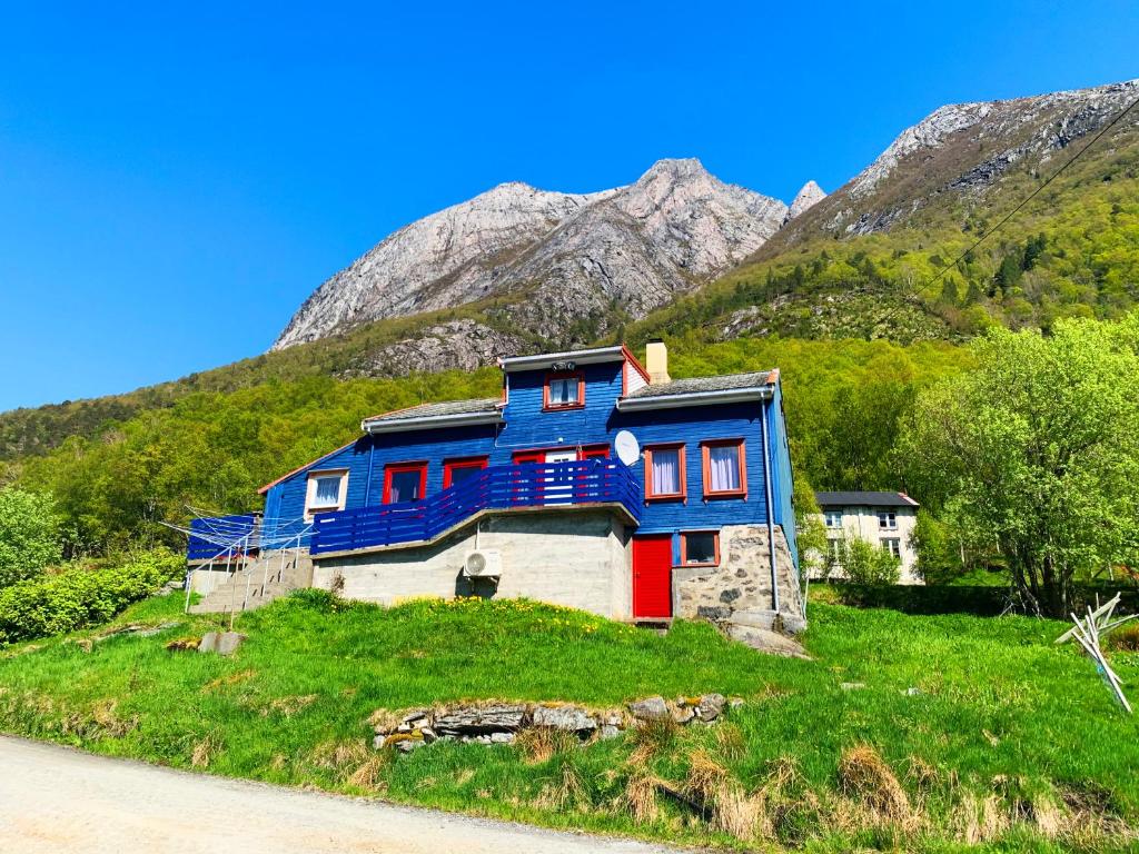 una casa azul en una colina con montañas en el fondo en Norway Stabben Tour, en Tustna