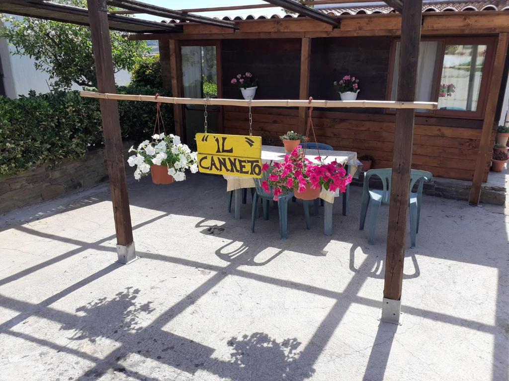a patio with a table with flowers and a sign at Il Canneto in Sassari