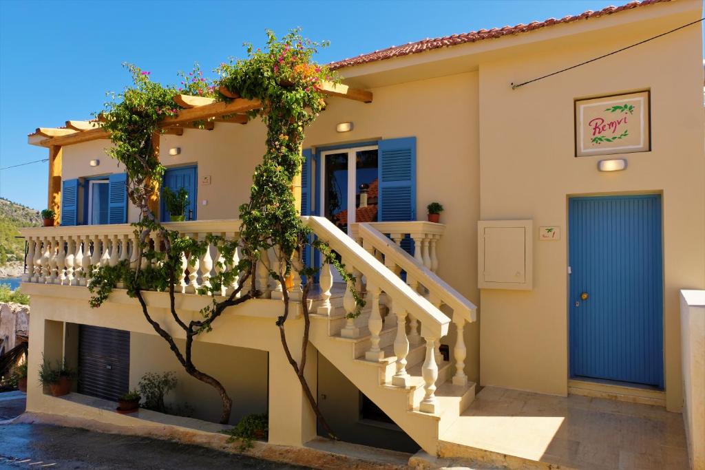 una casa con escaleras y una puerta azul en REMVI Apartments Assos, en Asos
