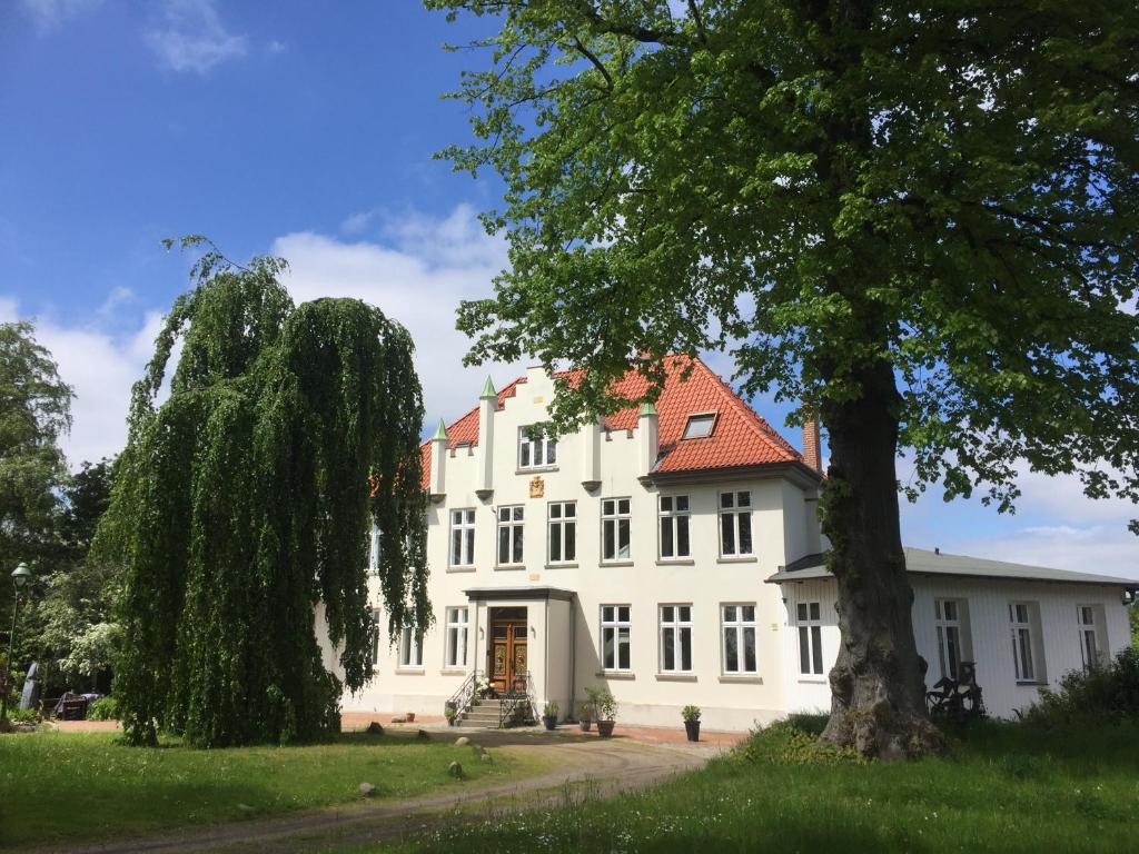 ein großes weißes Gebäude mit rotem Dach in der Unterkunft Herrenhaus Hohewarte in Lübeck