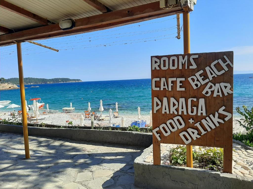 um sinal para um café perto de uma praia com o oceano em Paraga Rooms Pefkari em Pefkari